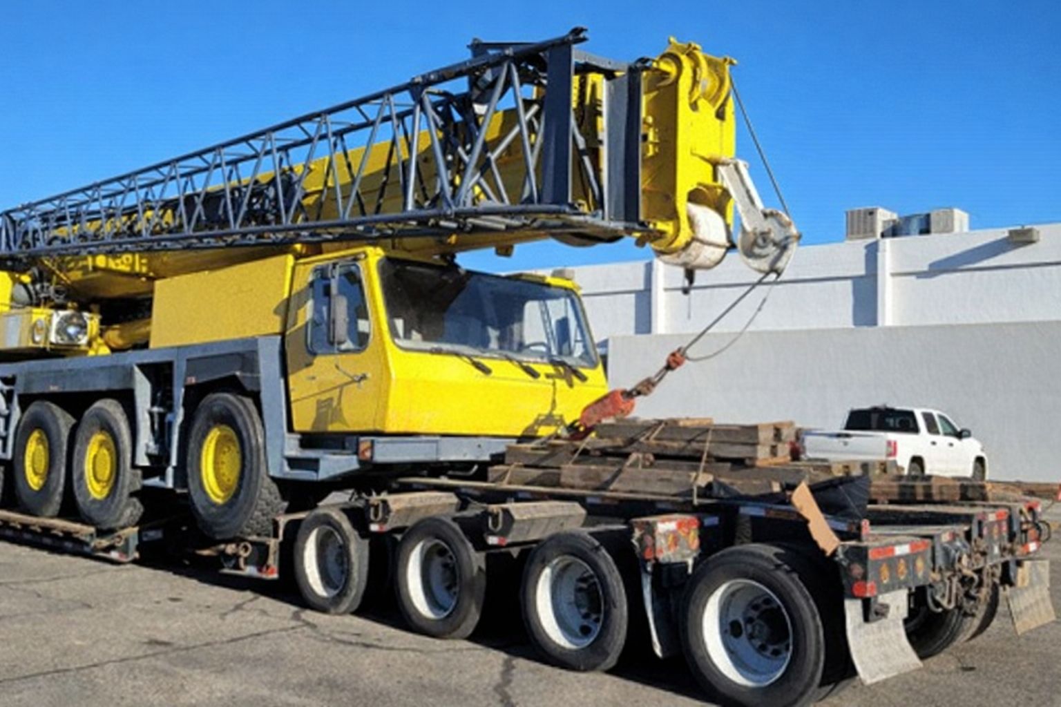 Gelber Kran auf Tieflader, bereit für den Transport zur Baumaschinen-Auktion.